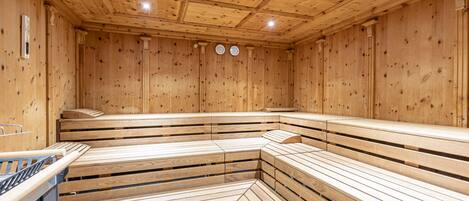Uma sauna com bancos de madeira e piso revestido de azulejos.