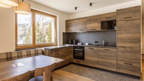 A modern kitchen with wooden cabinets, a built-in oven, and a window overlooking a forest. - Superior Lodge With Balcony (Hermagor-Pressegger See)