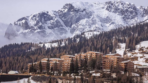 A mountain resort with multiple wooden buildings, snow-covered peaks, and dense forest. - Superior Lodge With Balcony (Hermagor-Pressegger See)