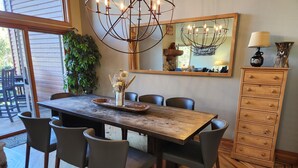 A dining area with a wooden table, six chairs, a chandelier, and a cabinet with drawers. - Snowcreek Resort Vacation Rental 733 (Mammoth Lakes)