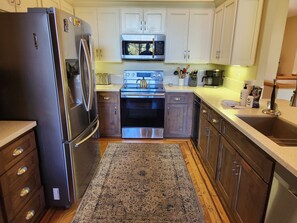A modern kitchen with stainless steel appliances, wooden cabinets, a microwave, and a built-in oven. - Snowcreek Resort Vacation Rental 733 (Mammoth Lakes)