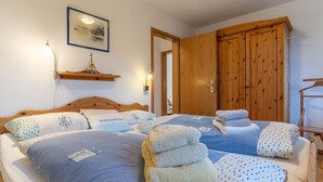 Ein Schlafzimmer mit zwei Betten, einem Holzschrank und einem Regal mit einem Schiffsmodell.