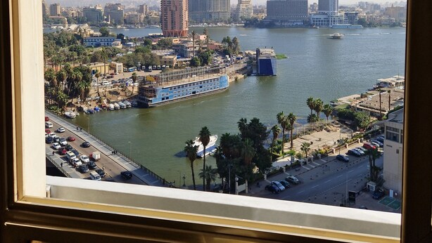A cityscape with a river, buildings, and a bridge. - Central Apt with a Panoramic view over Cairo & Nile (Giza Governorate)