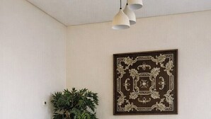 A dining area with a round wooden table, four upholstered chairs, a potted plant, and a framed artwork on the wall. - Central Apt with a Panoramic view over Cairo & Nile (Giza Governorate)