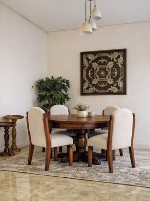 A dining area with a round wooden table, four upholstered chairs, a potted plant, and a framed artwork on the wall. - Central Apt with a Panoramic view over Cairo & Nile (Giza Governorate)
