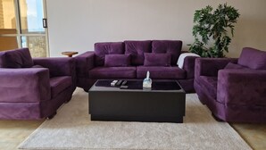A living room with a purple sectional sofa, a black coffee table, and a large window. - Central Apt with a Panoramic view over Cairo & Nile (Giza Governorate)