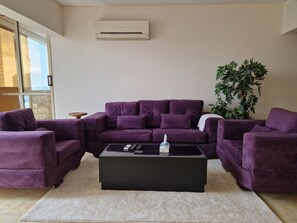 A living room with a purple sectional sofa, a black coffee table, and a large window. - Central Apt with a Panoramic view over Cairo & Nile (Giza Governorate)