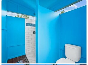 Une salle de bain avec des toilettes blanches, un espace douche et des murs bleus.