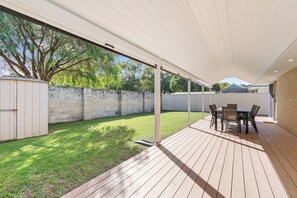 Une terrasse extérieure avec une table et des chaises, un espace abrité et un mur en pierre.