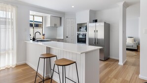 Une cuisine moderne dotée d’un grand îlot central, d’appareils électroménagers en acier inoxydable et de tabourets de bar en bois.