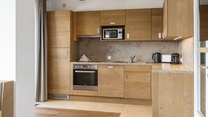 Una cocina moderna con armarios de madera, microondas integrado, horno y cafetera.