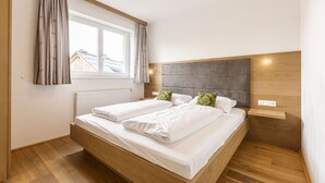 Un dormitorio moderno con una cama de madera, un cabecero gris y una ventana con cortinas.