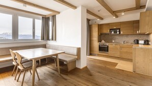 Una cocina moderna con armarios de madera, microondas integrado y un amplio ventanal con vistas a un paisaje nevado.