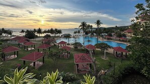 A resort with a large swimming pool, palm trees, and beach views.