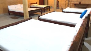 A room with three wooden beds, each with white bedding. There is a wooden table and a chair in the room. - Sinharaja Eco Lodge  (Neluwa)