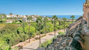 A coastal residential area with houses, palm trees, and a clear view of the sea.