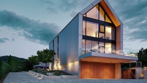 Un bâtiment moderne doté d’un toit en pente, de grandes fenêtres et d’une terrasse en bois.