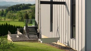 Un bâtiment moderne doté d’un balcon, d’un escalier et offrant une vue sur un paysage verdoyant.