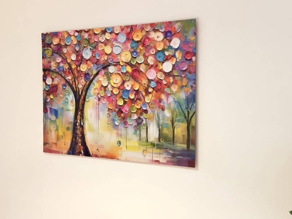 Une peinture abstraite aux couleurs vives, représentant un arbre et des motifs circulaires.