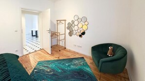 Ein modernes Wohnzimmer mit einem grünen Sessel, einem bunten Teppich und einer Wandgestaltung.