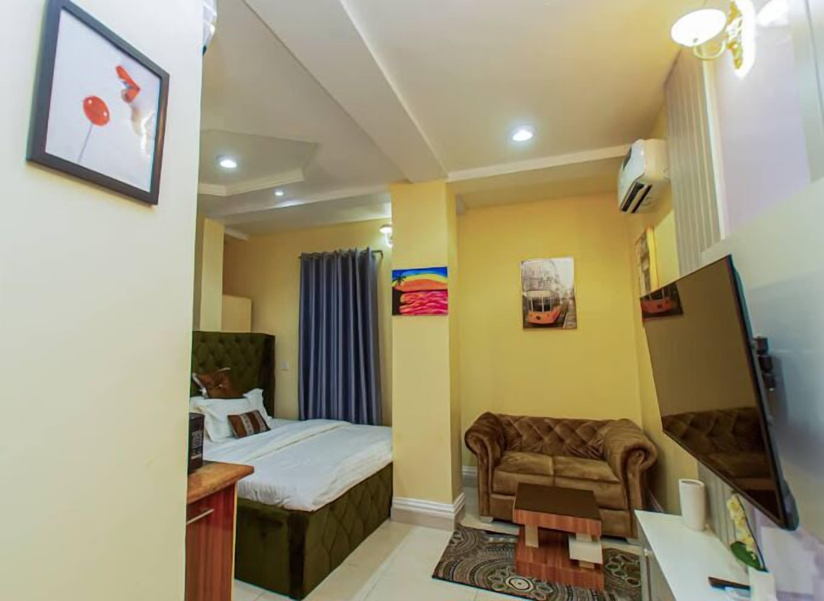 A compact hotel room with a bed, a sofa, a small table, and a TV.