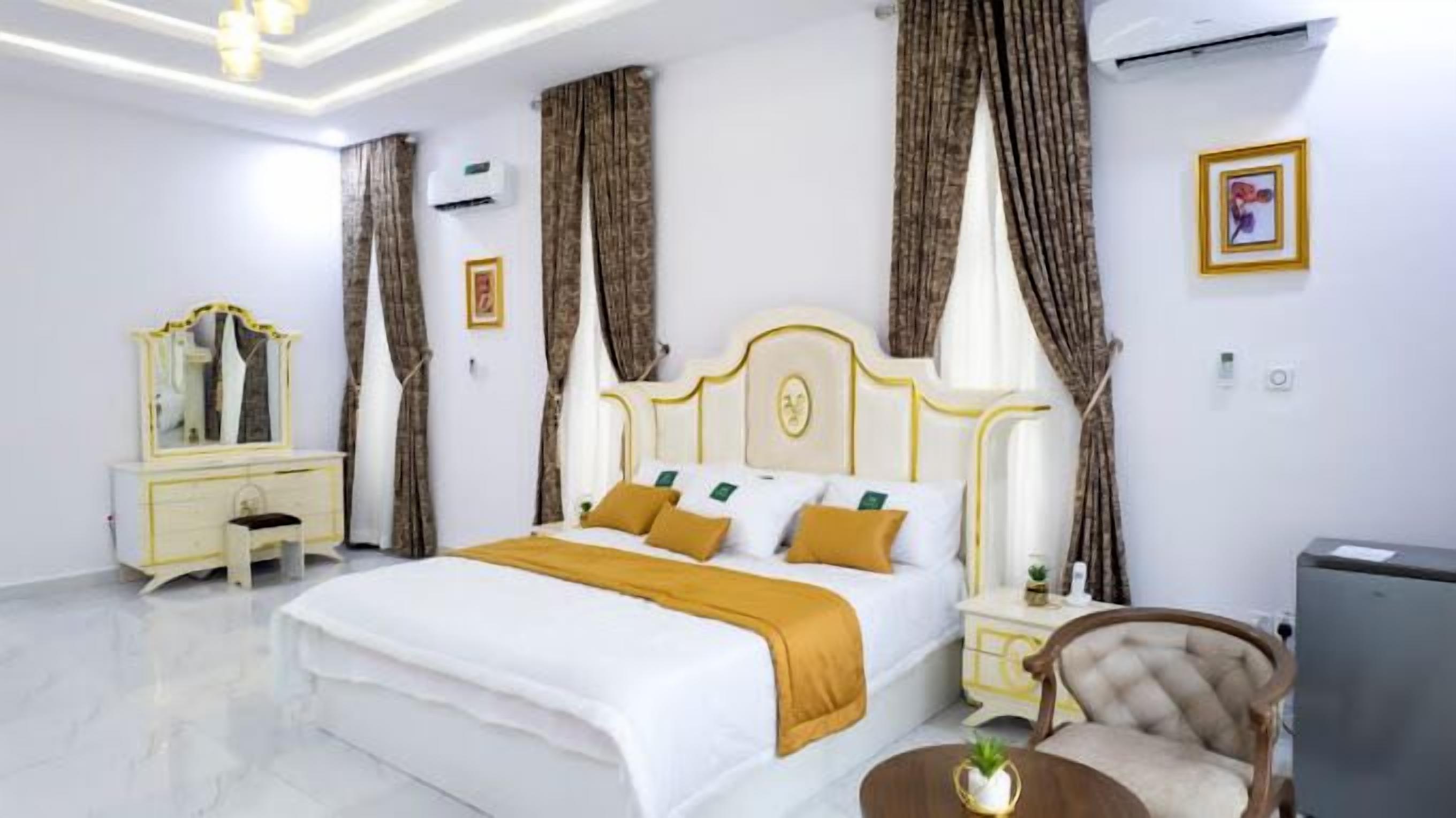 Una habitación de hotel con una cama grande, una mesita de noche, una silla y un equipo de aire acondicionado.