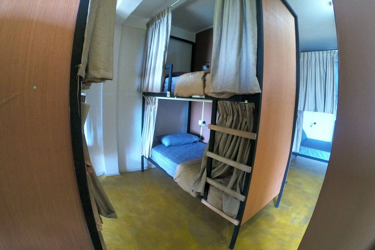 Habitación con literas, cortinas, una escalera y una ventana.