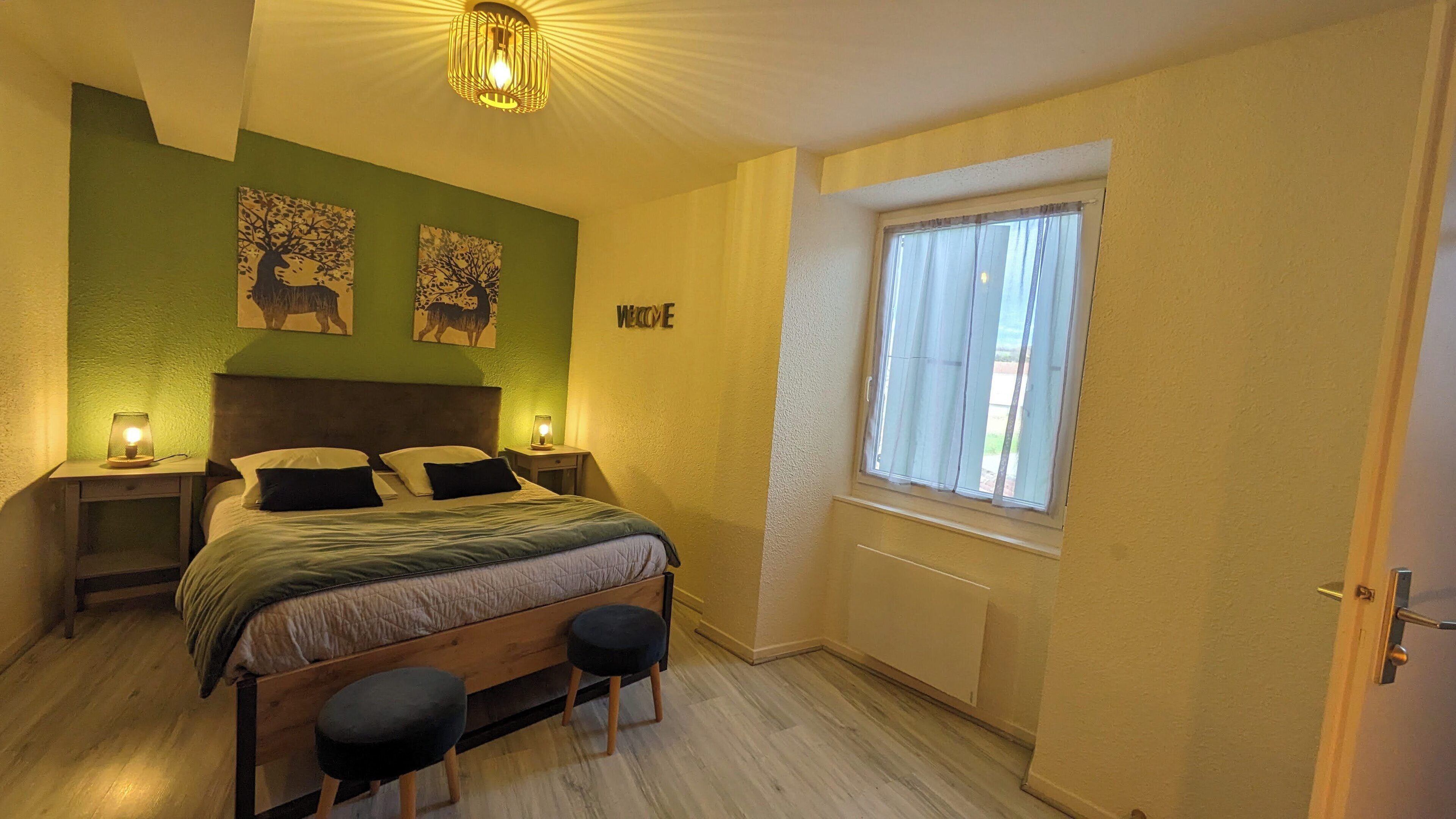 A bedroom with a bed, two nightstands, a window, and artwork on the wall.