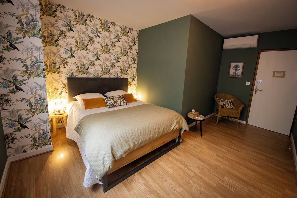 Quarto com cama, mesa de cabeceira, cadeira e porta.