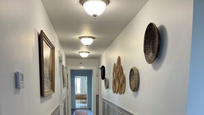 A hallway with wooden flooring, white walls, and decorative wall art. - Lake Jackson beachfront home w/dock, pool table, close to restaurants/shops (Sebring)