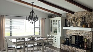 A dining area with a wooden table and chairs, a chandelier, and a stone fireplace. - Lake Jackson beachfront home w/dock, pool table, close to restaurants/shops (Sebring)