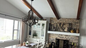 A dining area with a wooden table and chairs, a chandelier, a stone fireplace, and a white cabinet. - Lake Jackson beachfront home w/dock, pool table, close to restaurants/shops (Sebring)