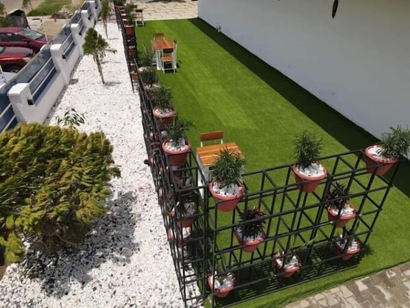 A rooftop garden with a neatly trimmed lawn, potted plants, and a seating area. - The Coral Luxury Apartment (Abuja)