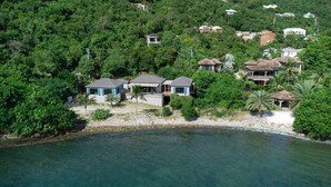 A coastal property with multiple houses surrounded by dense greenery and a clear view of the ocean. - Monarch Cottage Waterfront Fish Bay, Pebble shoreline, A/C, Generator (St. John)