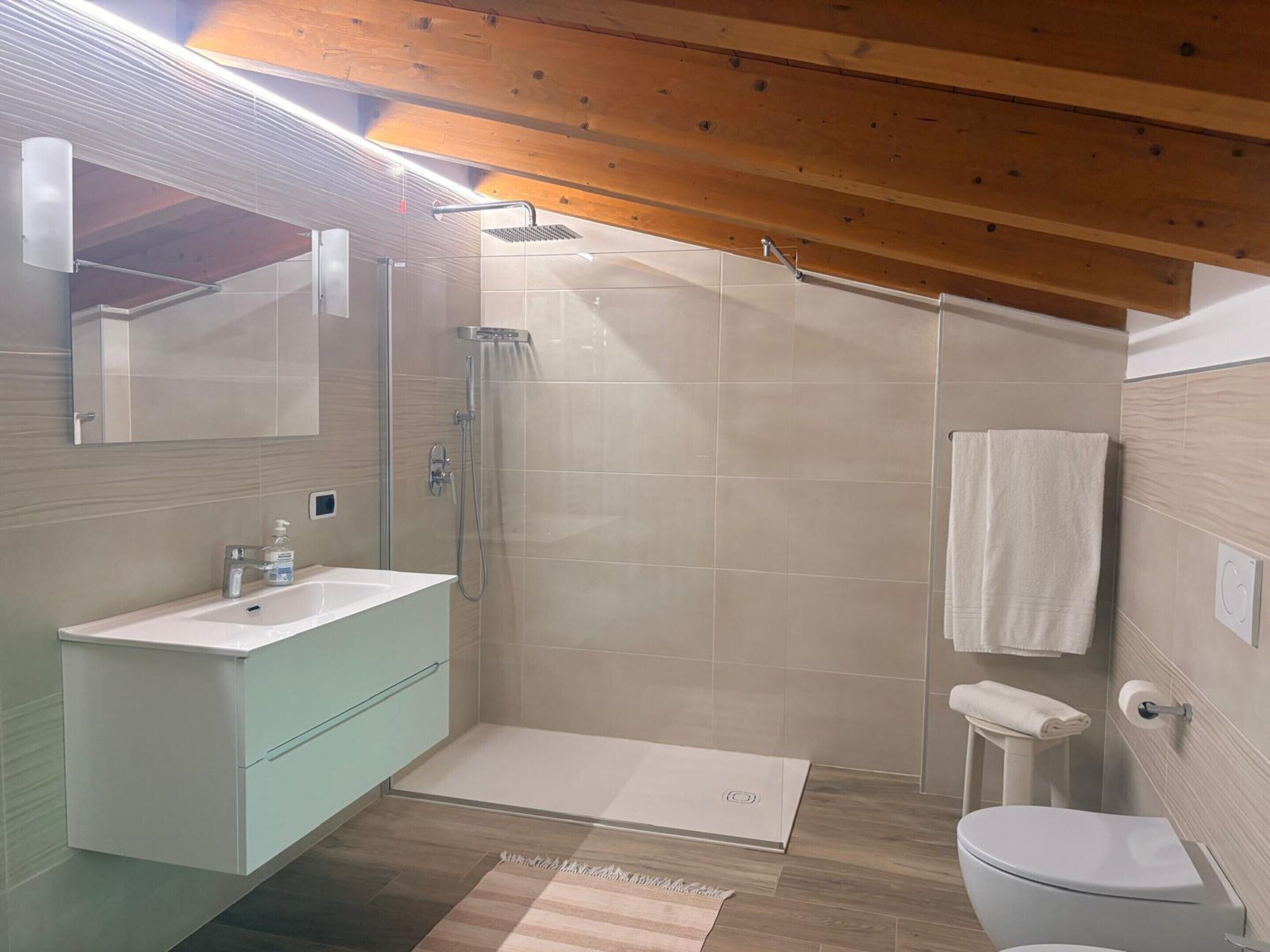 A modern bathroom with a shower, toilet, and sink.