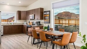 Une cuisine moderne avec des meubles en bois foncé, un réfrigérateur en acier inoxydable et un coin repas comprenant une table en bois et des chaises en cuir.
