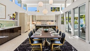 A modern kitchen with a dining area, large windows, and a view of the outdoors. - Webb House – Mid-Century Modern in Vista Las Palma (Palm Springs)