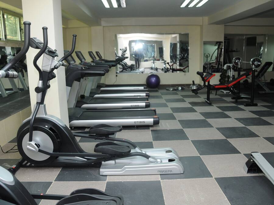 A gym with multiple treadmills, exercise bikes, and a mirrored wall.
