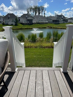 A wooden deck with a view of a pond and houses in the background.