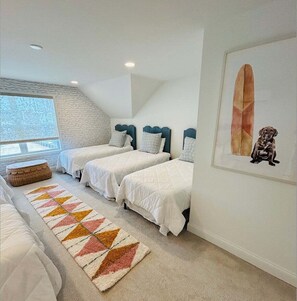 Ein Schlafzimmer mit zwei Betten, einem Fenster, einem gerahmten Bild und einem gemusterten Teppich.