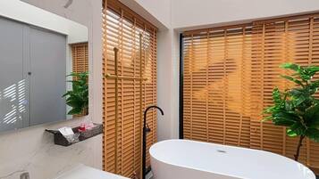 A modern bathroom with a freestanding bathtub, a vanity with a mirror, and wooden blinds.
