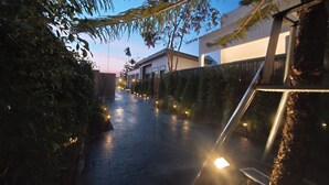 A pathway lined with trees and illuminated by string lights, leading to a building with a modern design. - S'Villa  (Warin Chamrap)
