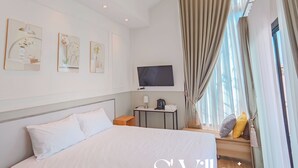 A hotel room with a large bed, a desk with a lamp, a television, and artwork on the walls. - S'Villa  (Warin Chamrap)