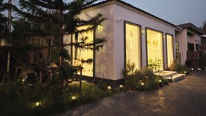 A modern house with large windows, a well-lit entrance, and a garden with small lights. - S'Villa  (Warin Chamrap)