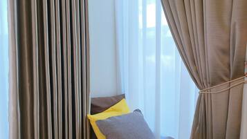 A hotel room with a bed, a wooden bench, and curtains.