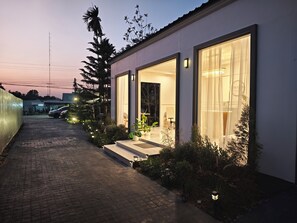 A modern house with large windows, a paved driveway, and outdoor lighting. - S'Villa  (Warin Chamrap)