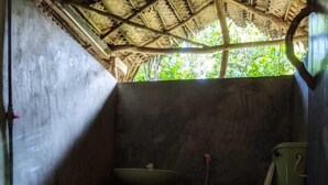 Ein kleines, schlichtes Badezimmer mit Betonboden, einem grünen Waschbecken und einer Toilette.