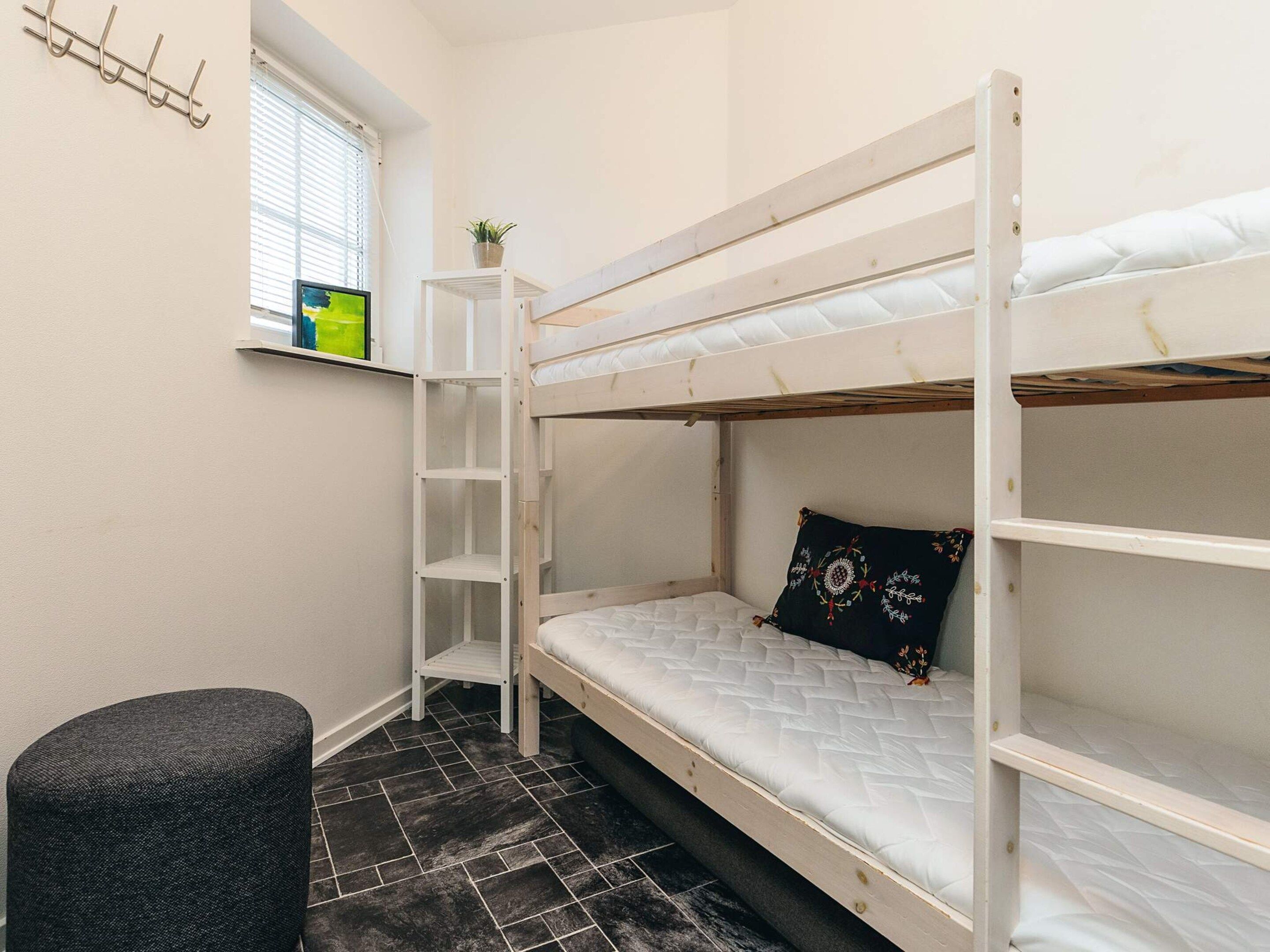 A bunk bed room with a window, a small table, and a chair.