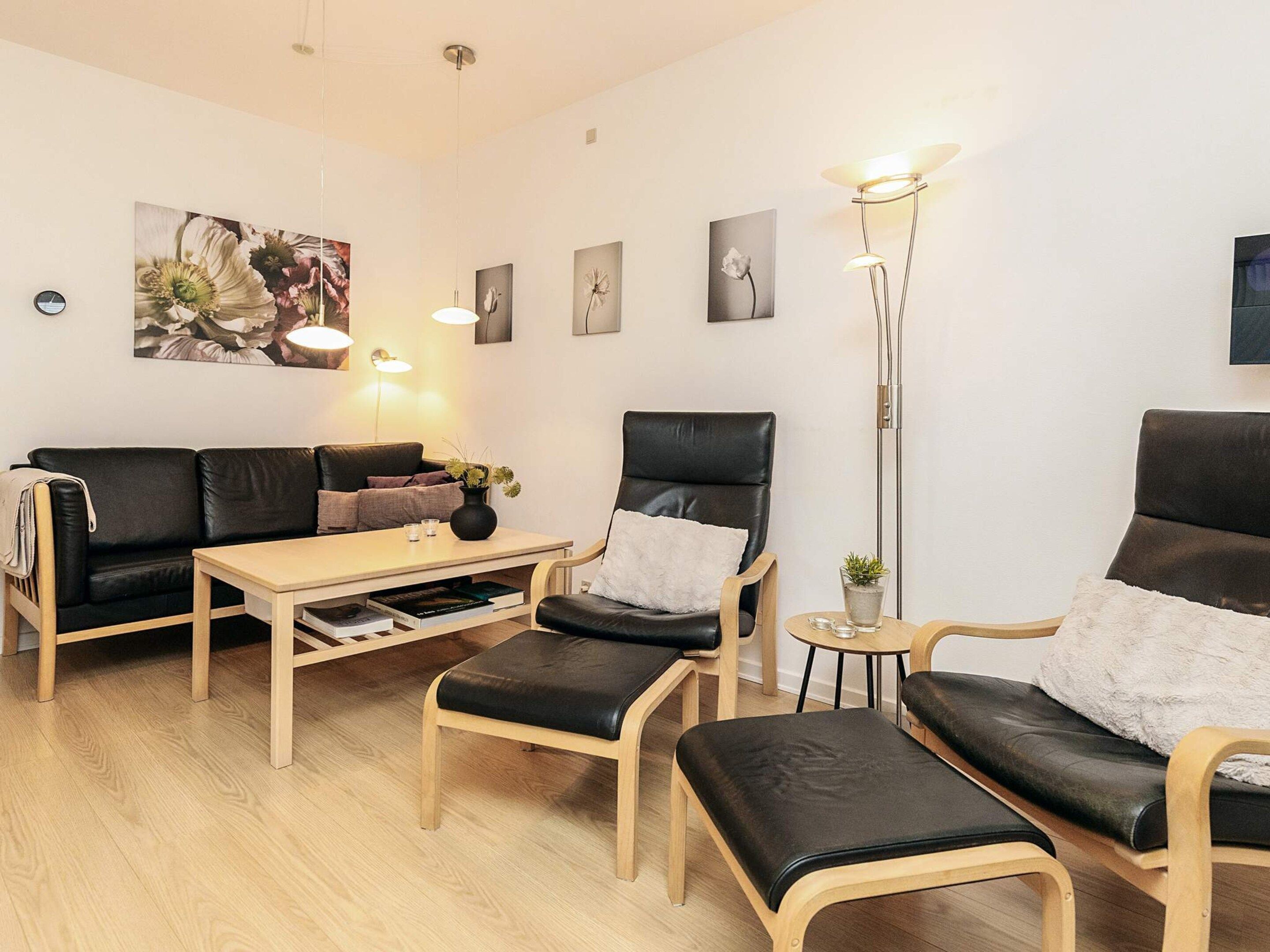 Een moderne woonkamer met een bank, twee fauteuils, een salontafel en een vloerlamp.