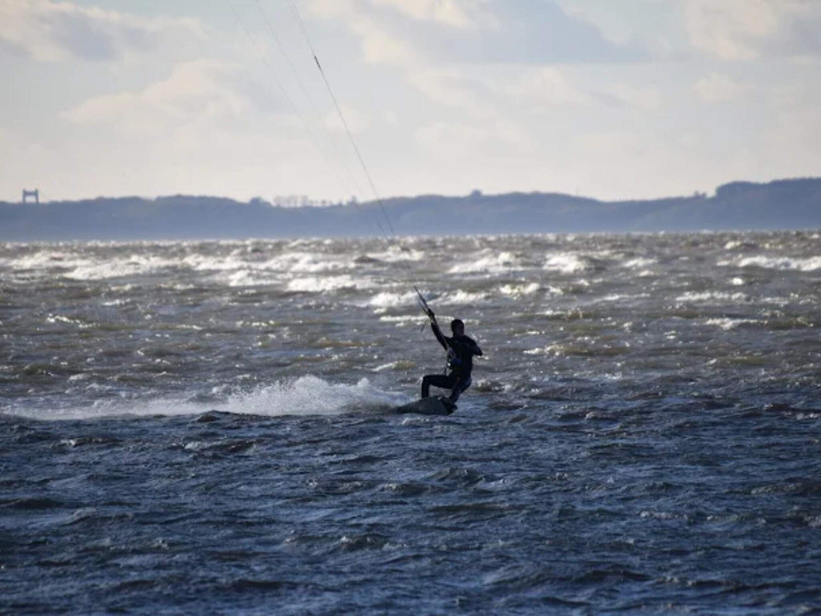 Una persona practica windsurf sobre aguas con olas.